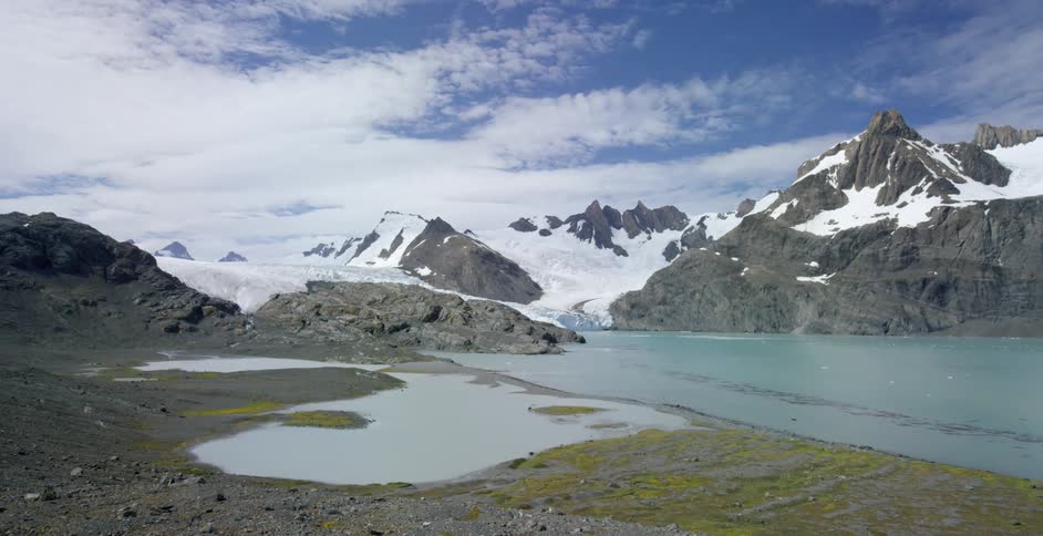 A valley has a small pond and mountain range