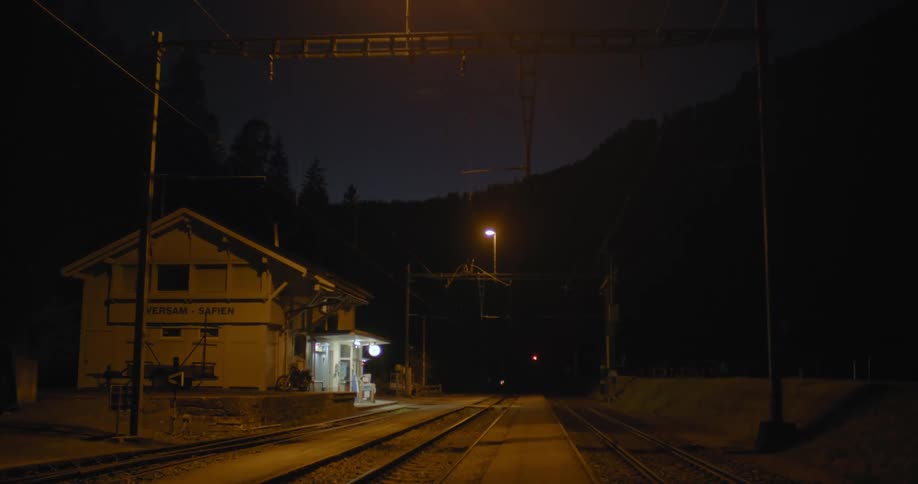 Train tracks next to a building with trees and the sky and the background