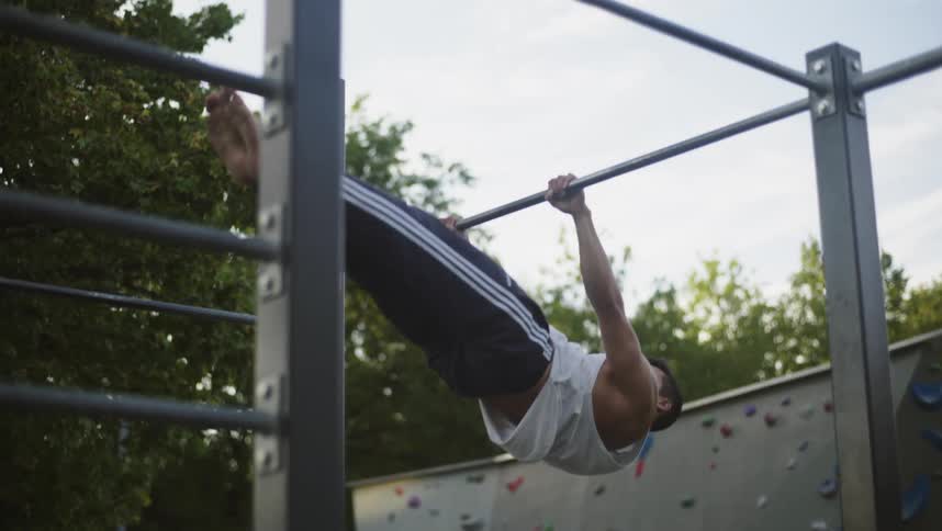A man is doing pull ups in the park
