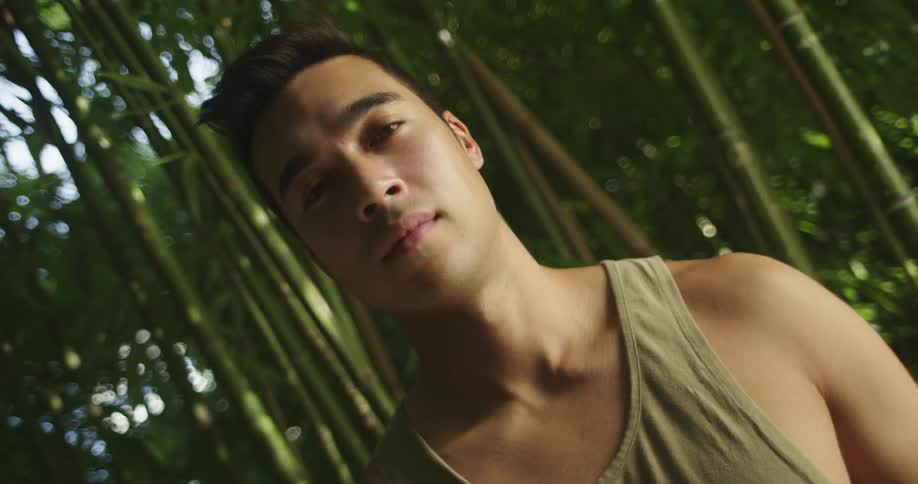 Man stands in bamboo forest wearing a tank top