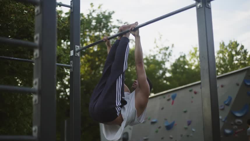 A man is hanging from the bar in the park