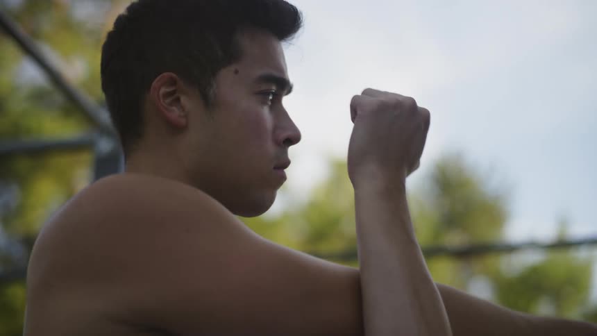 A man stretching with trees the sky and clouds in the background