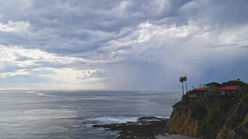 The sun breaks through the clouds of a thunder and lightning storm on the coast
