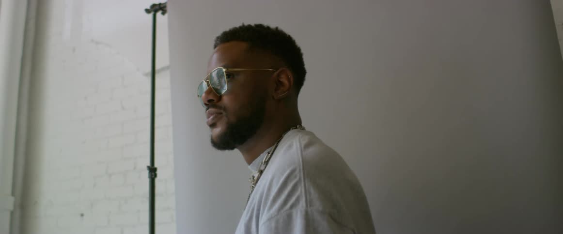 Young man wearing sunglasses modeling in front of a backing