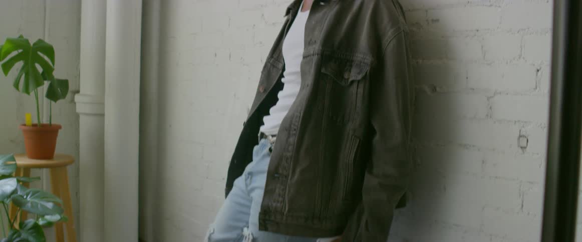 Young male model reclining on a white brick wall on a photoshoot