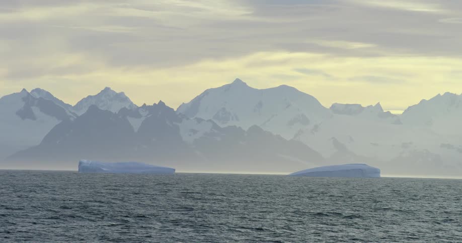 Ice floats in the water near a mountain range