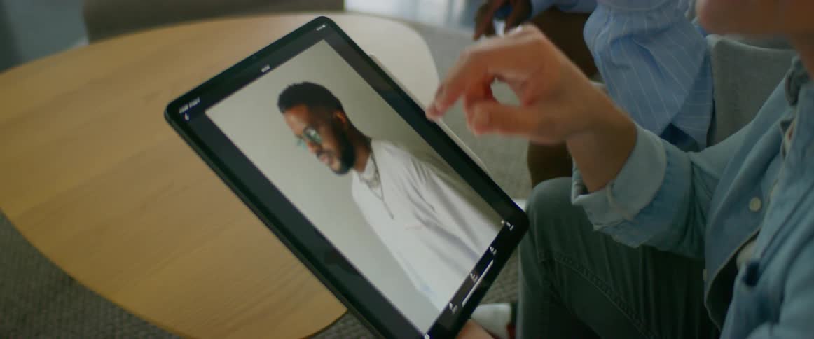 Two people look at pictures on a tablet and talk