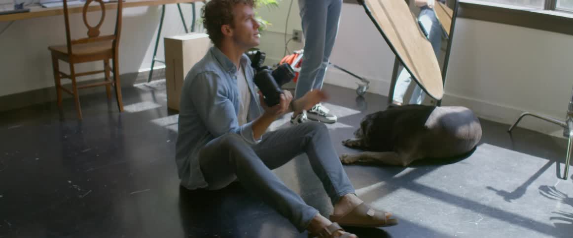 A man taking photos with a camera while another person holds a mirror