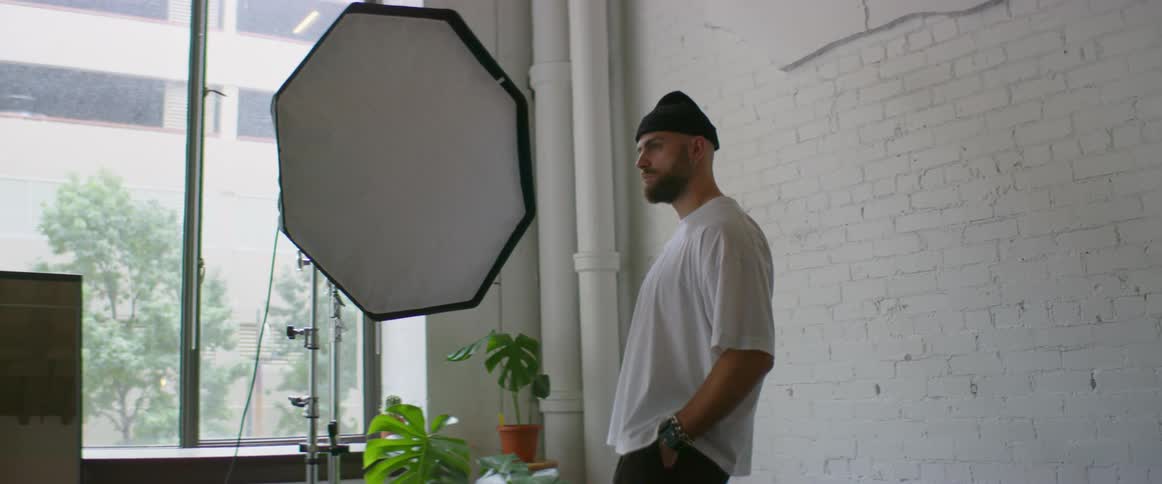 Model poses against white painted brick wall in photography studio