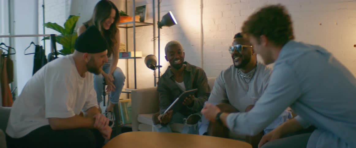 Group of friends sitting on the couch looking at pictures on a tablet
