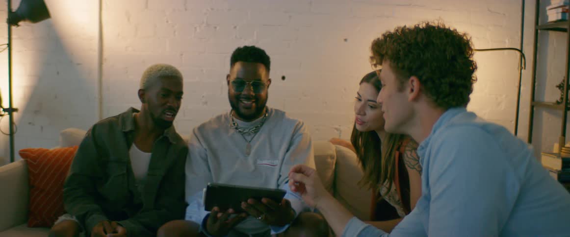 A group of friends look at photographs on a tablet