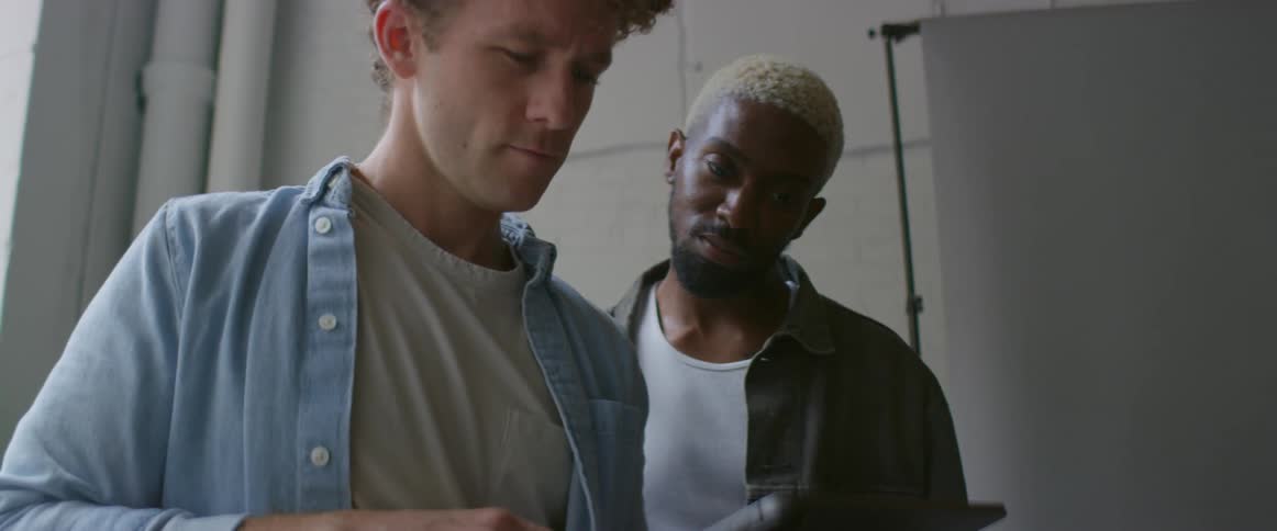 Two young men looking at pictures on a tablet inside a photo studio