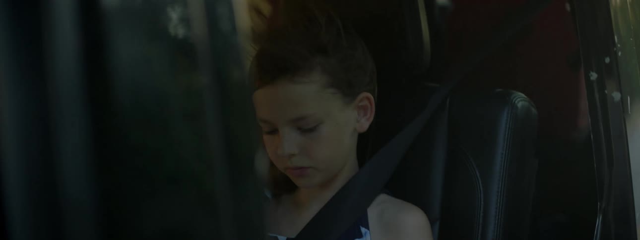 Young girl sitting on a driving vehicle gets her hair blowed by the wind
