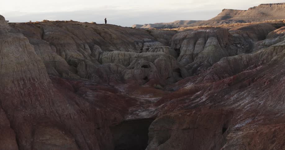 Person walking on the edge of the cliffs on a mesa in the badlands