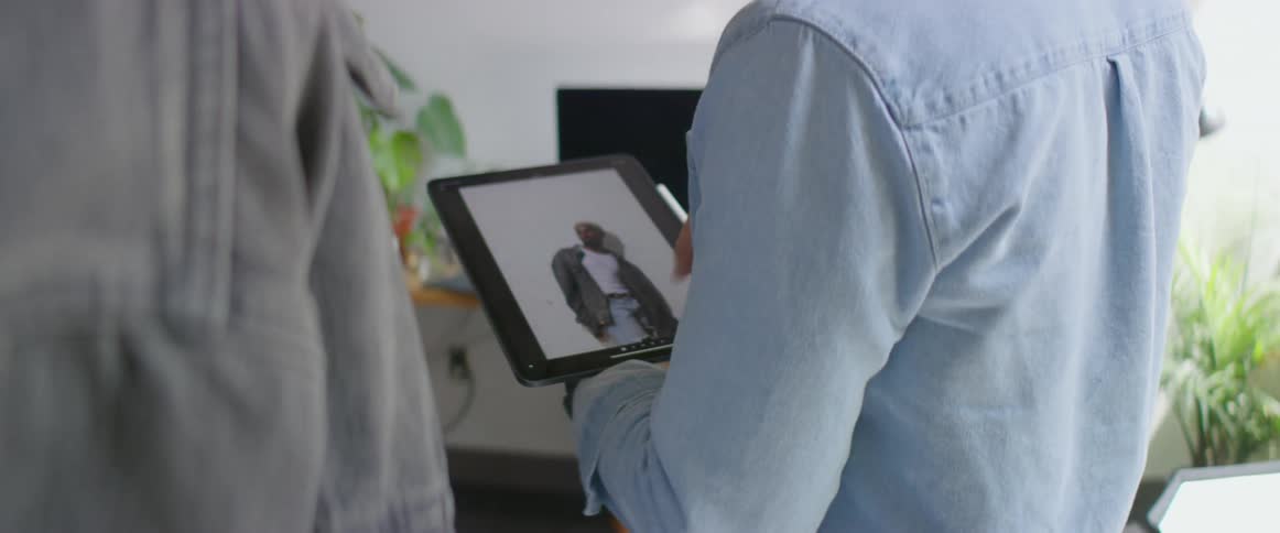 Two men standing in a room looking at pictures on a tablet