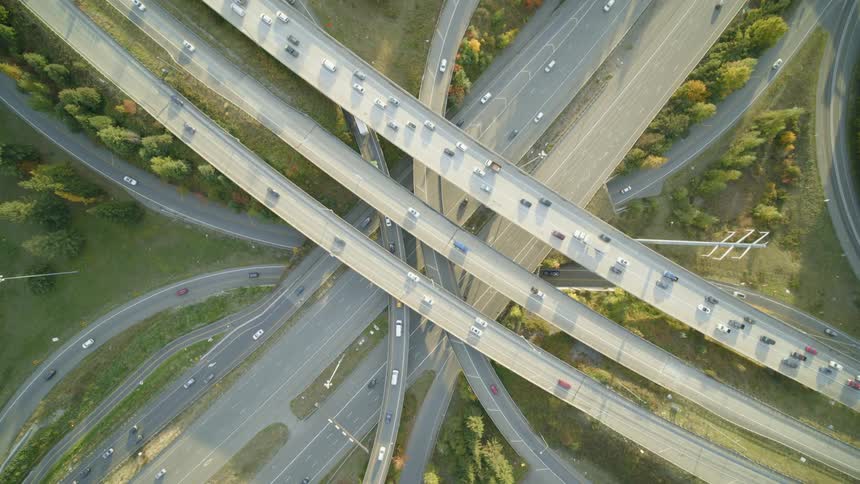 Top down twisting view of traffic flowing along a multi level highway interchange