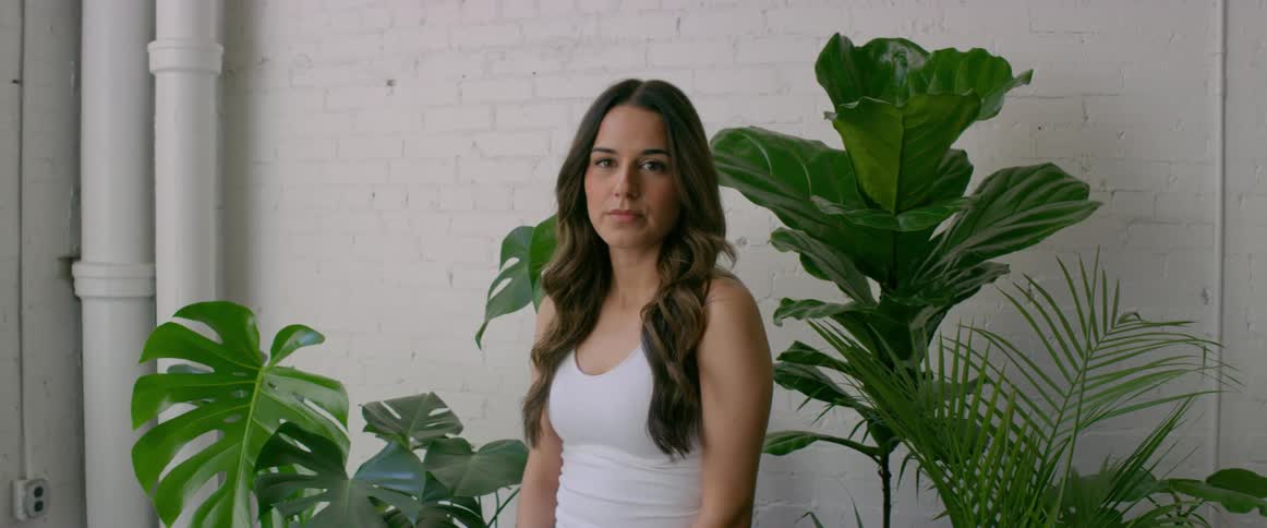 Young woma standing in front of house plants modeling for the camera