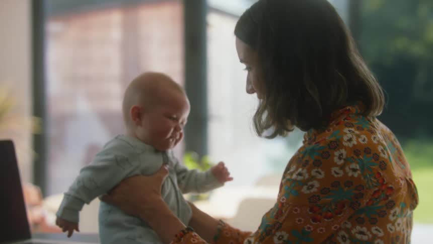 Mother playing with her toddler over the desk at home