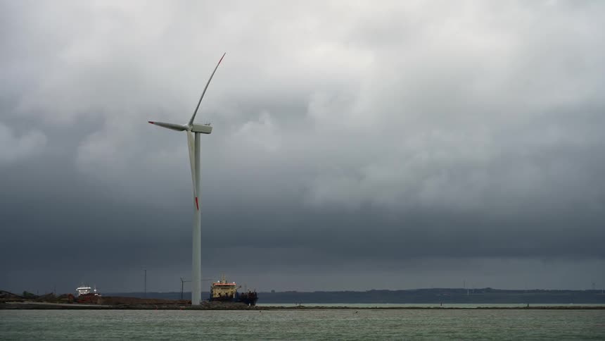 The windmill is turning near the shore
