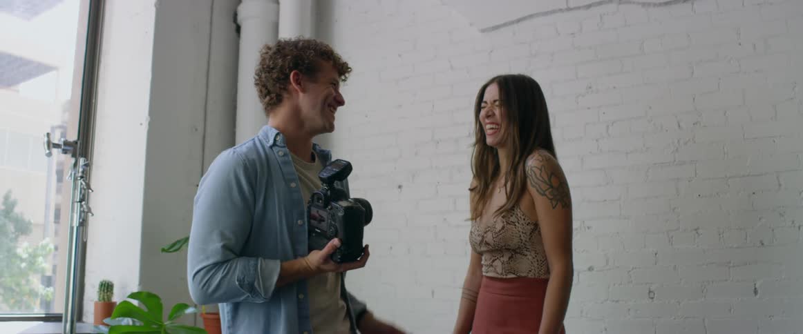 Photographer and woman laugh while previewing pictures on camera