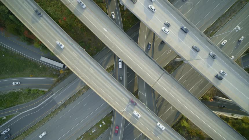 Overhead traverse of traffic driving along a multi level interchange during the evening commute