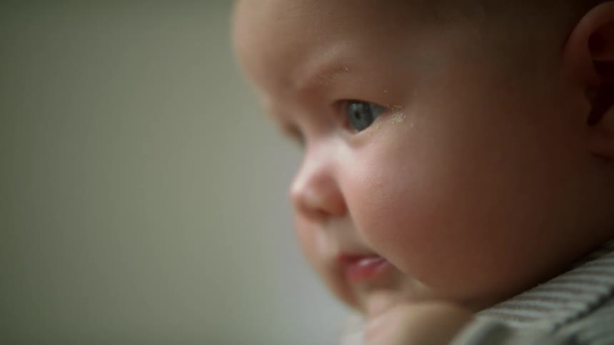 A baby looks around and raises his hand