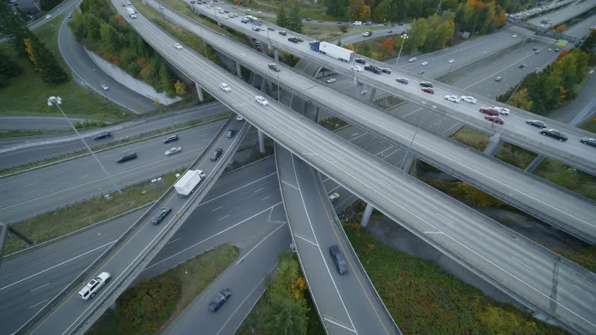 Tilt up reveal of traffic flowing at different speeds through a stacked multi lane interchange