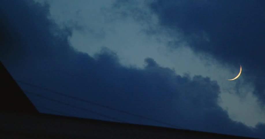 Clouds move across the sky making a crescent moon visible