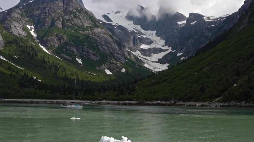 A lake with a boat with a mountain range the sky and clouds in the background