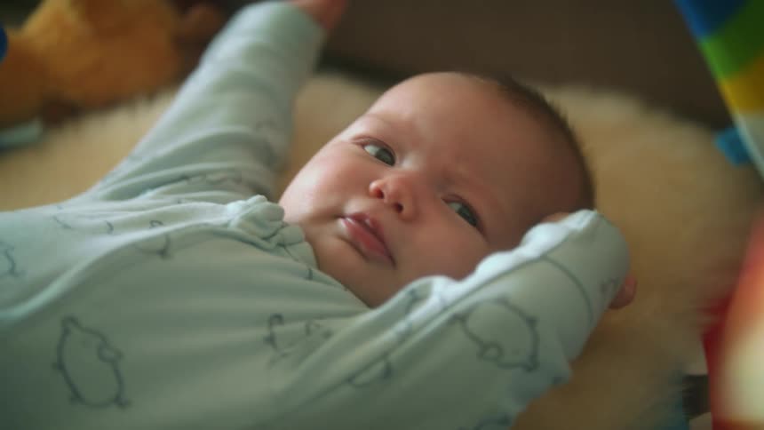 Baby laying in bed at home moving while looking at something
