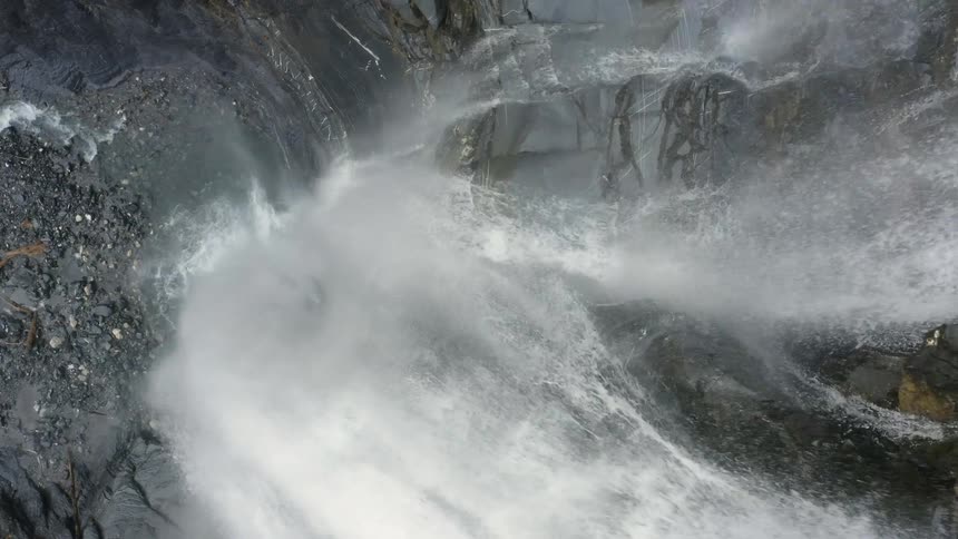 Water rushes down the face of a cliff into the rocky basin