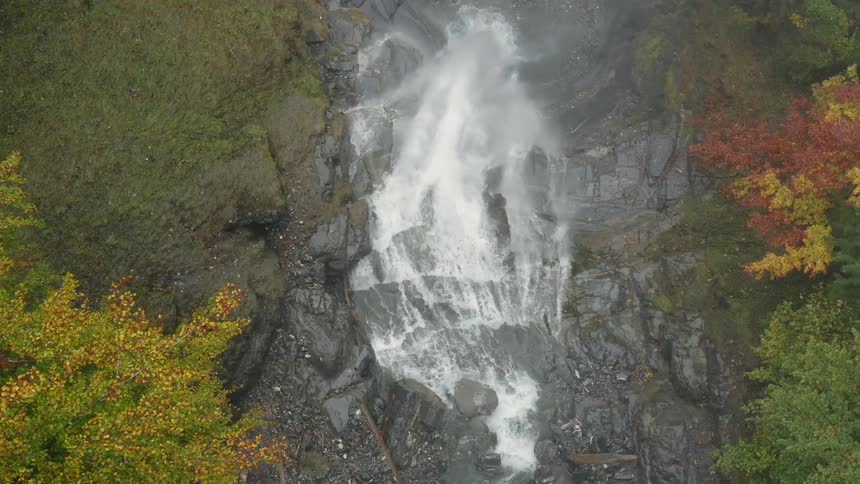 Aerial view of a river turning into a waterfall over the rocks on a mountain