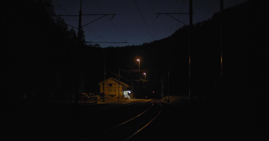 Train tracks next to a building with trees and the sky in the background