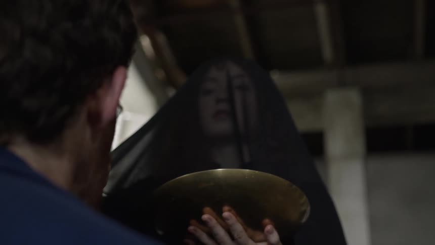 A woman with a veil holding a bowl and touching a mans forehead