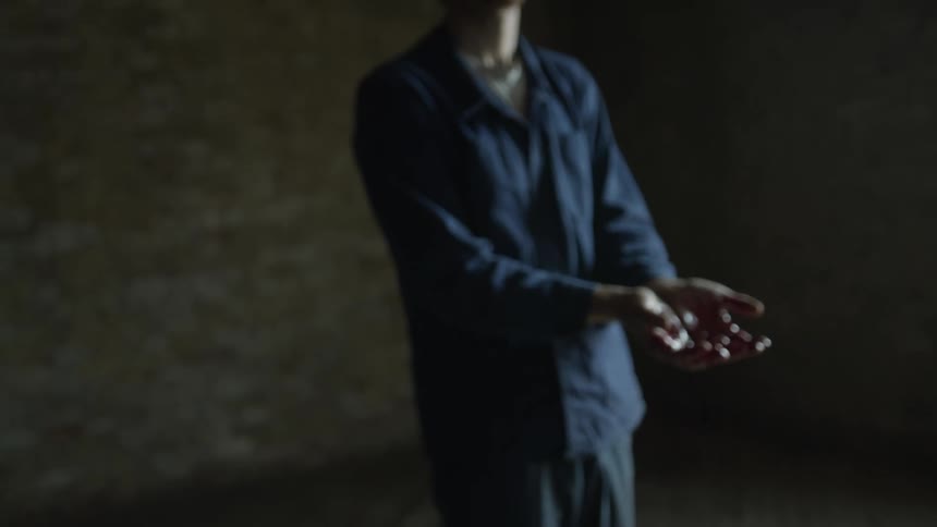 Young man standing inside an empty room wih his hands dripping in bright red blood