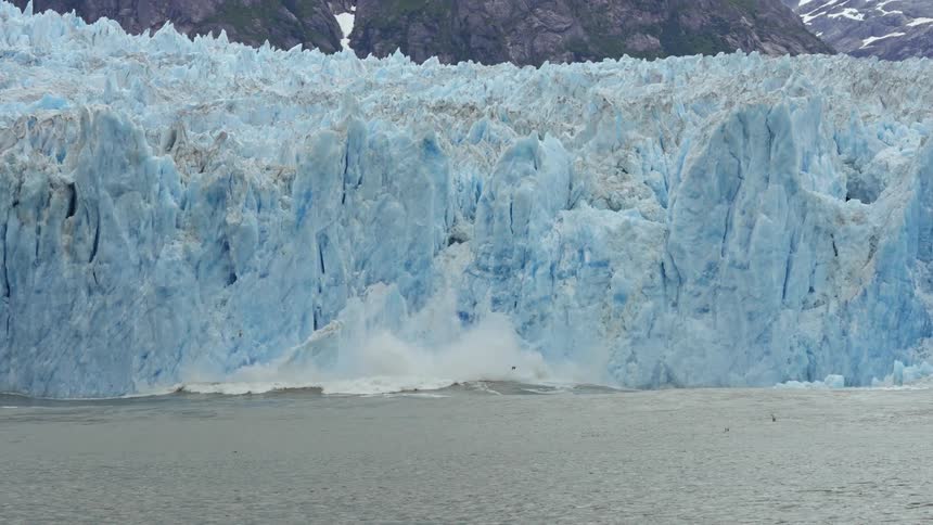 A section of a glacier breaks off and falls into the ocean