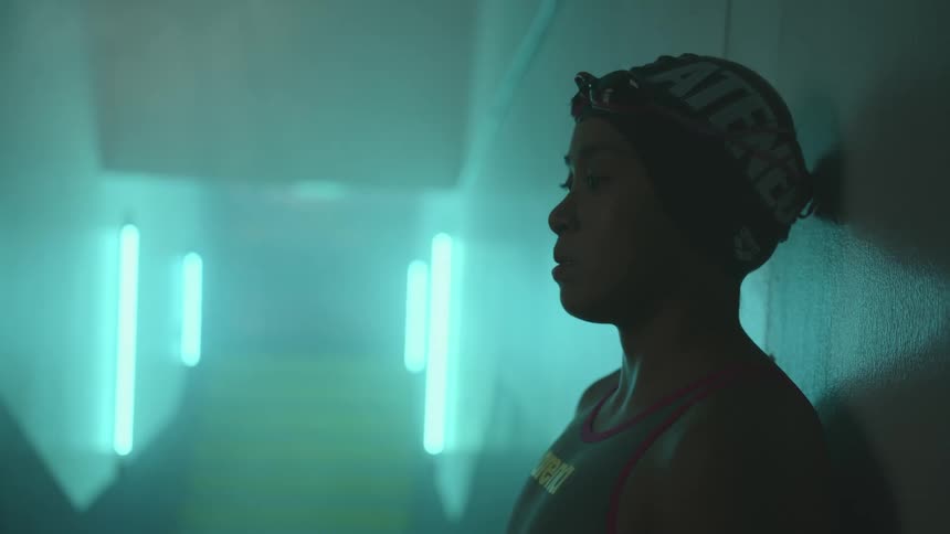A woman in a corridor with a bathing suit goggles and a swimming cap