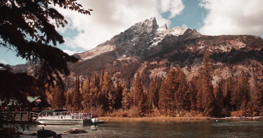 Ferry docking on a lake in front of the pine tree forest in the mountains