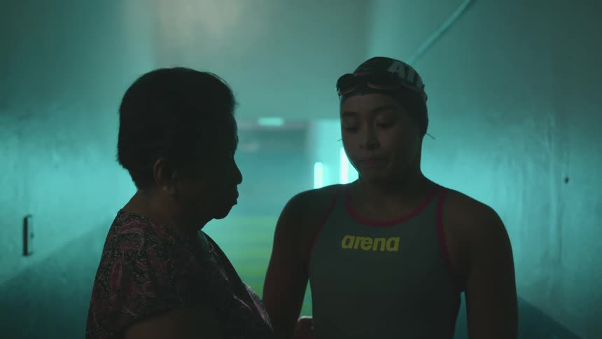 Mother arranges the sports clothes on her daughter while standing on a hallway