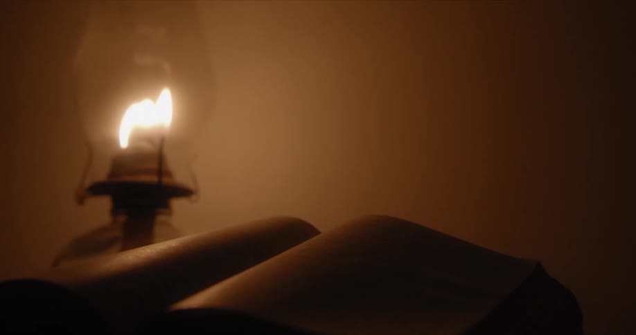 The old oil lamp sits near the open book