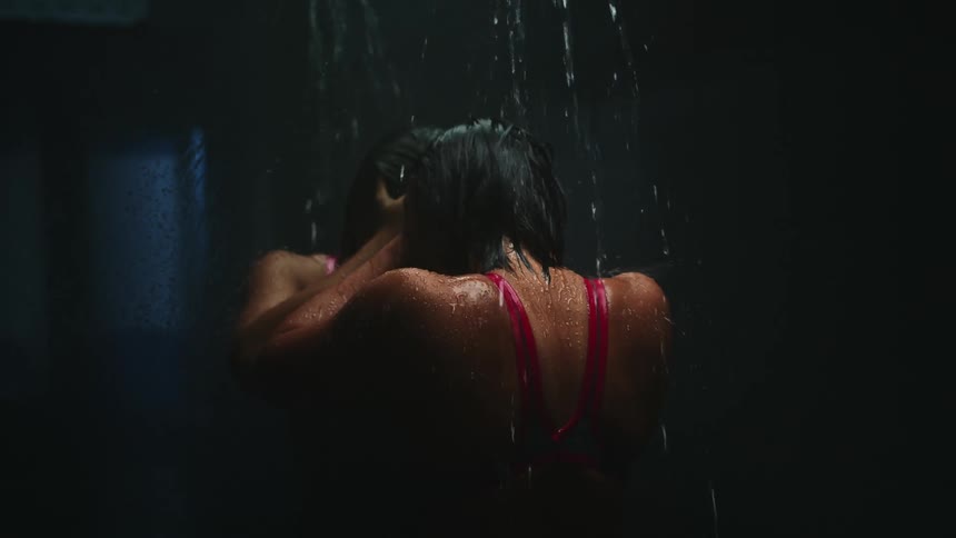 A woman with a bathing suit standing in front of a mirror with water dripping on her back