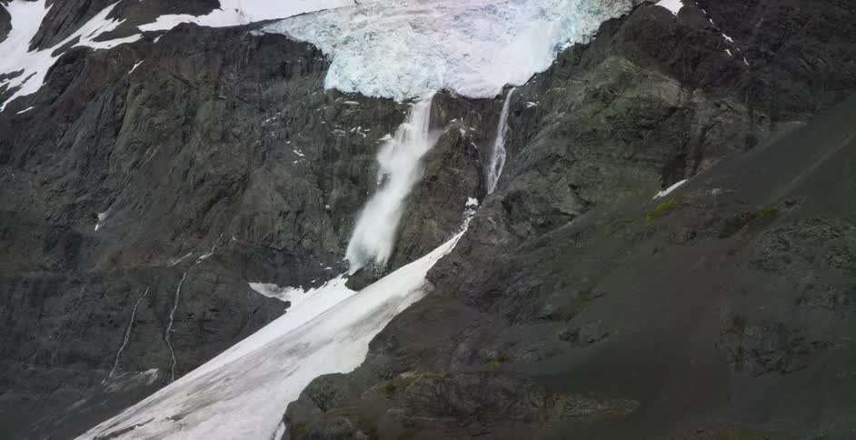 Water pours down from a snow covered mountain top