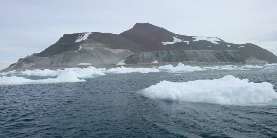Ice floats in the water near the shore of a mountain