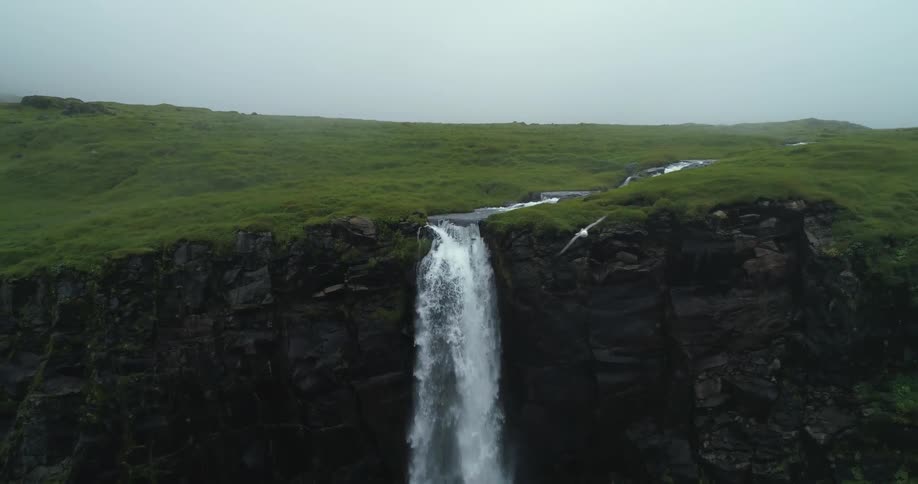 Birds are flying around waterfalls falling over a cliff