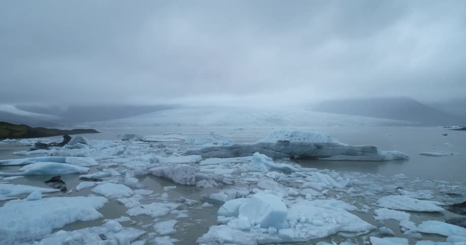 A landscape with glaciers and water with the sky and clouds in the background