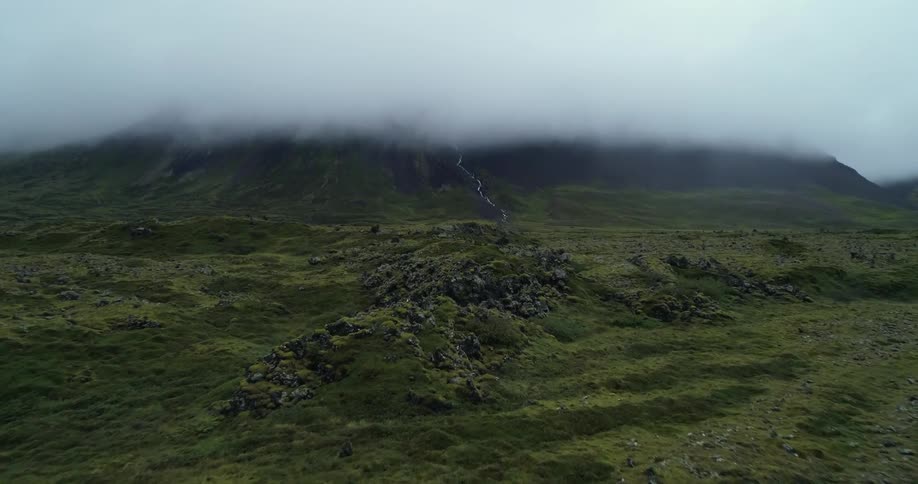 The green hills lead to a mountain range