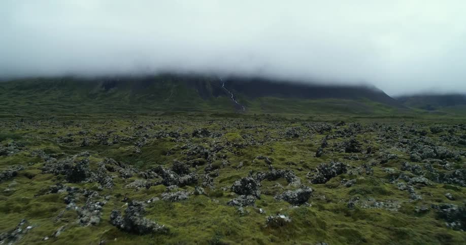 Ground covered in grass and rocks and a hazy smoky sky in the distance