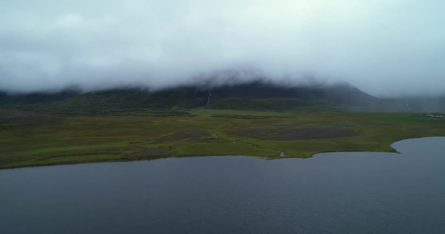 The heavy clouds cover the mountains by the shore
