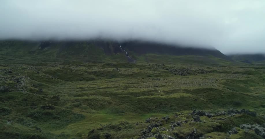 An aerial view of a hilly landscape with mountains shrouded in thick fog in the daytime