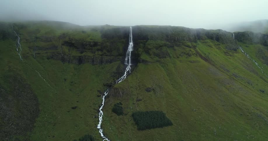 Fog obscures mountain tops as water falls down cliff in twin waterfalls